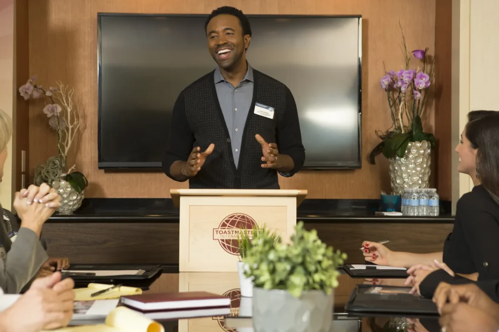 A confident speaker smiles while presenting from the lectern